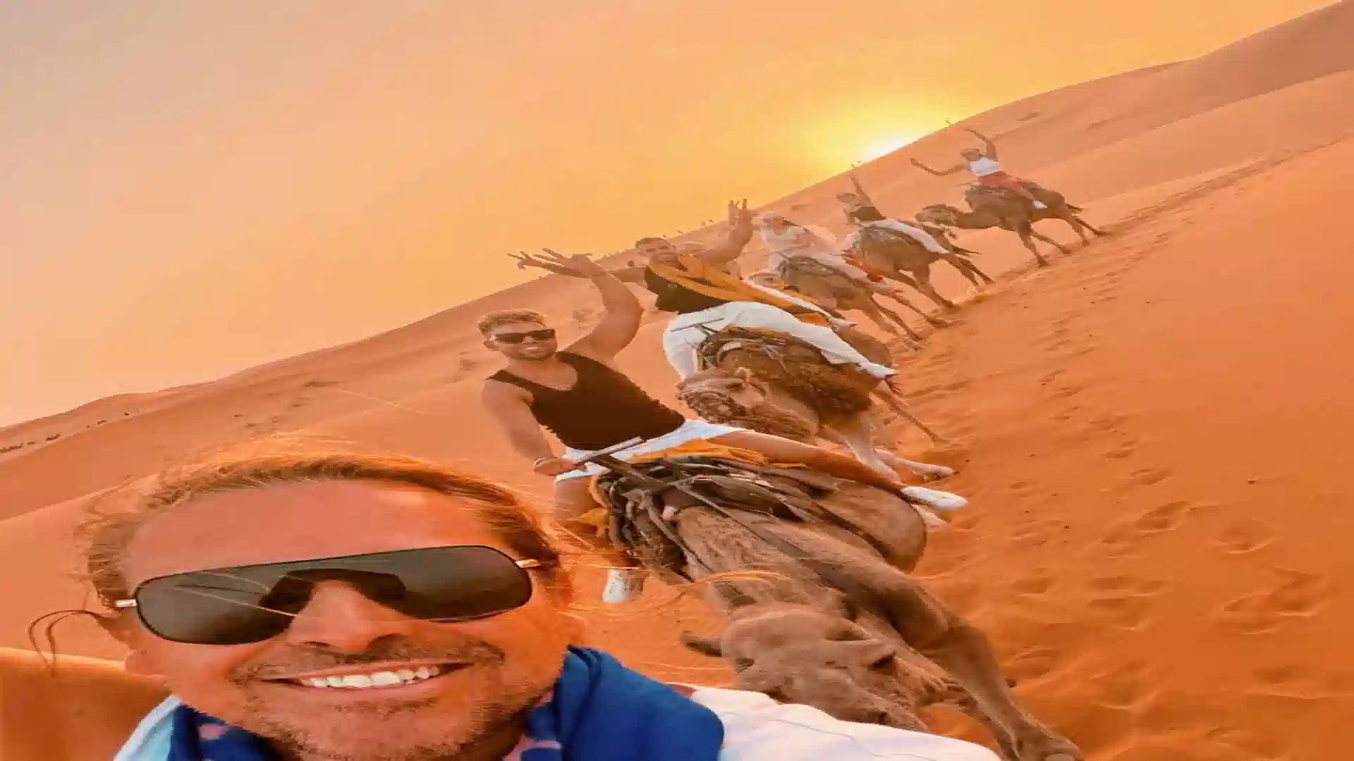 best Sahara Desert tour from Marrakech - travelers riding camels through the Erg Chebbi dunes