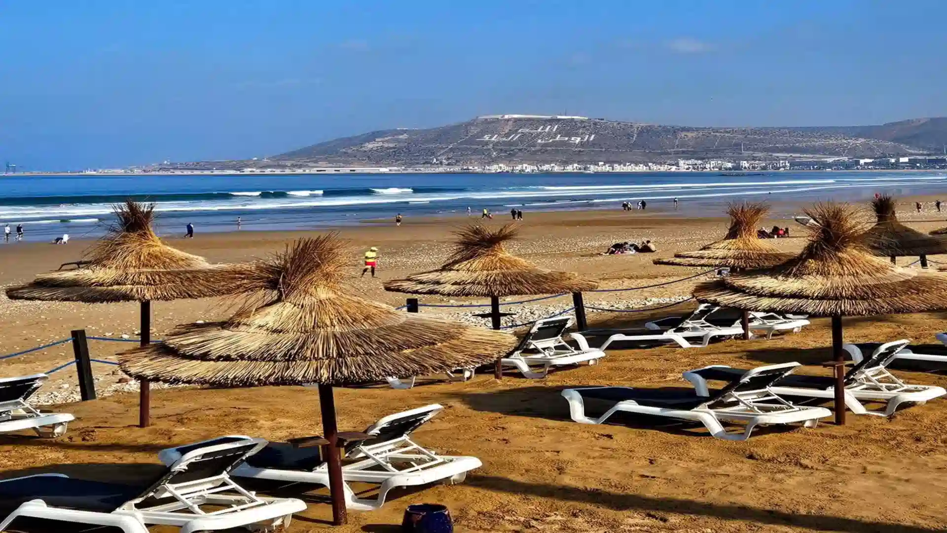 Agadir beach resort area with straw umbrellas and lounger chairs facing Agadir Oufella hill during a 12 days tour from Agadir to Marrakech
