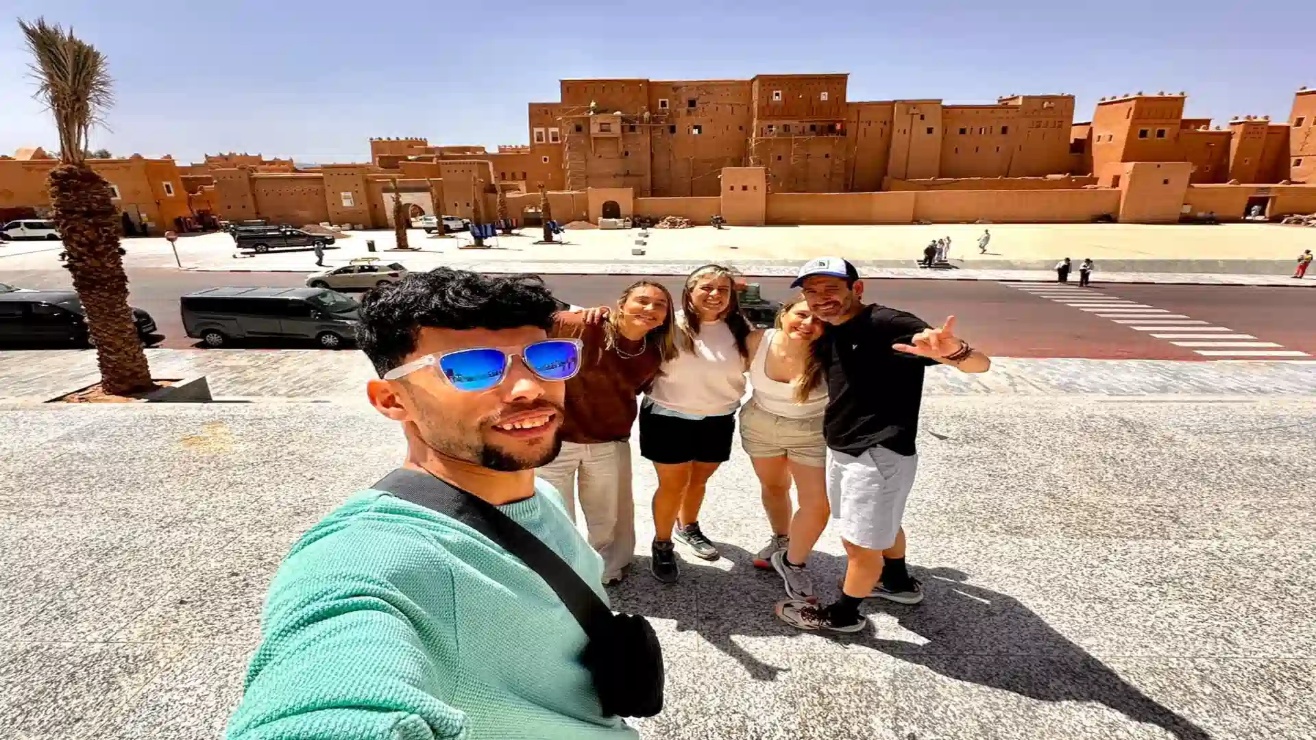 Happy travelers taking a group selfie in front of Kasbah Taourirt in Ouarzazate during a 10 days tour from Agadir Morocco