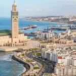 High-angle aerial view of the Hassan II Mosque standing along the turquoise Atlantic Ocean with the Casablanca cityscape in the background. things to do in Casablanca