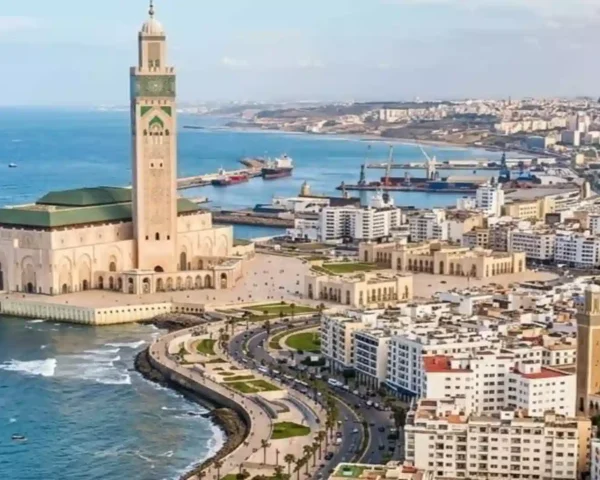 High-angle aerial view of the Hassan II Mosque standing along the turquoise Atlantic Ocean with the Casablanca cityscape in the background. things to do in Casablanca