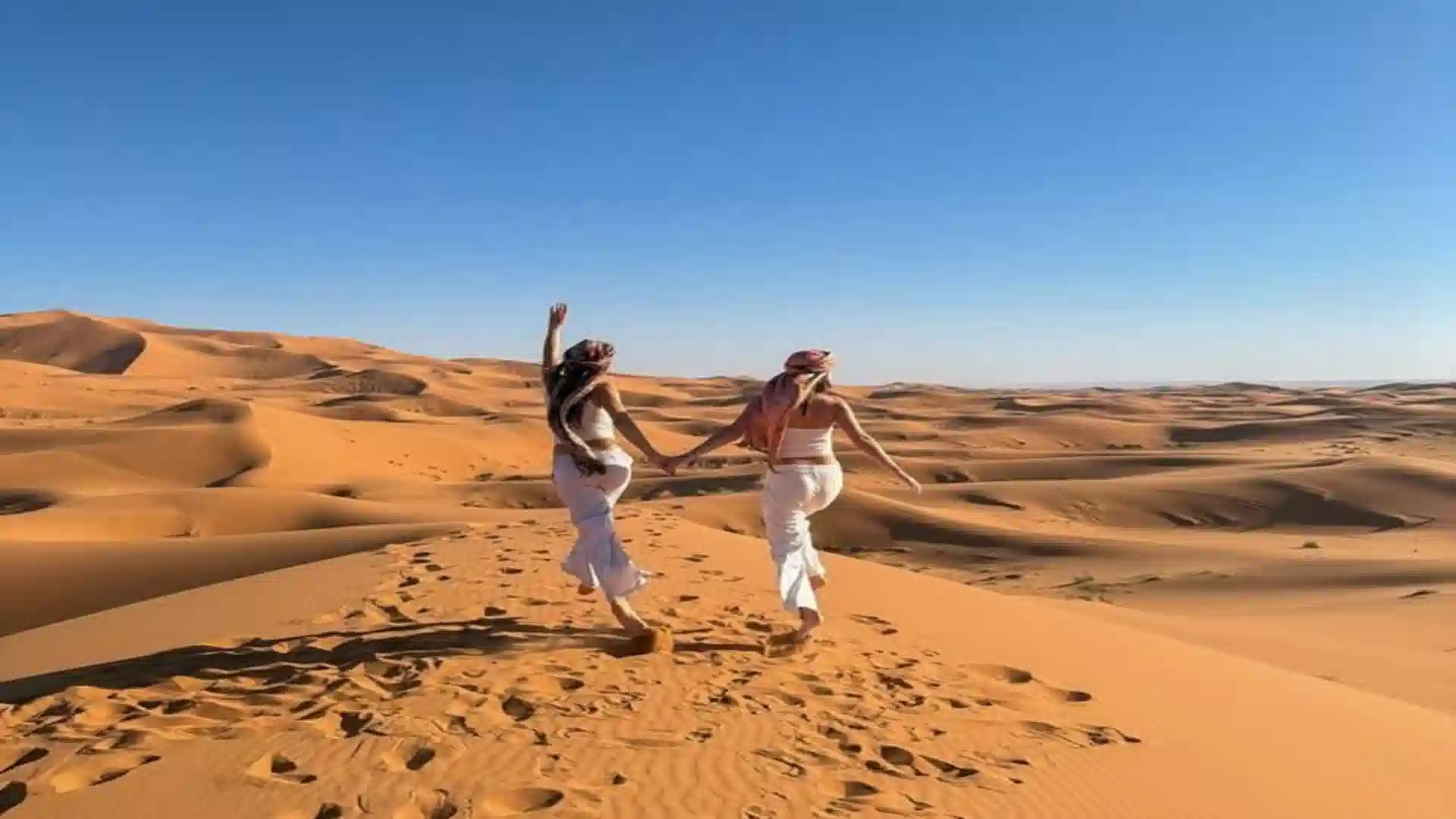 Travelers on the Erg Chebbi dunes near Merzouga at sunset