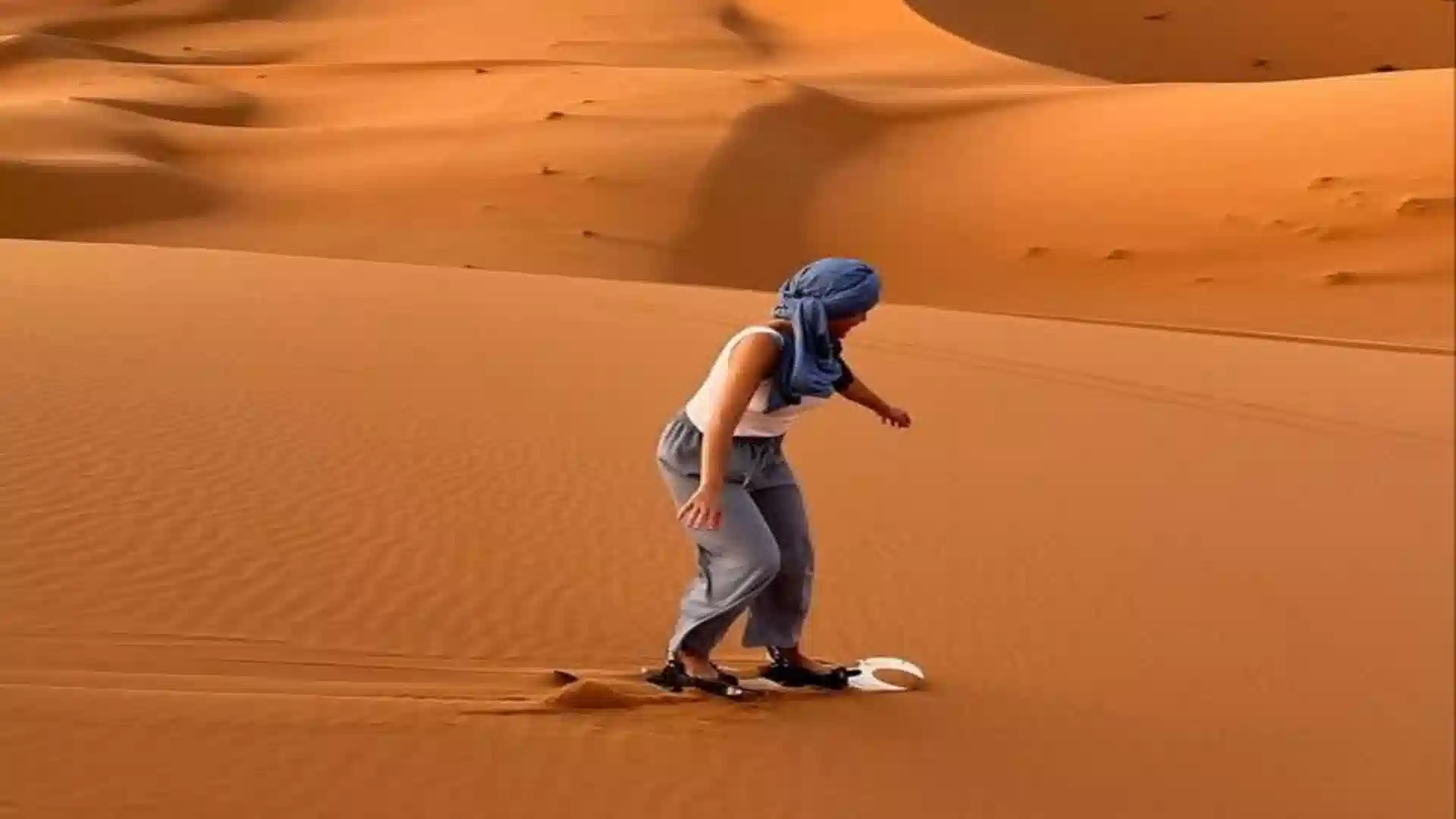 Sandboarding down a dune near Merzouga on the Marrakech to Merzouga route